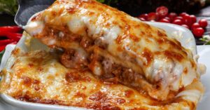 Receita de lasanha de carne moída com molho branco gratinada em uma travessa, com camadas de molho, queijo derretido e massa