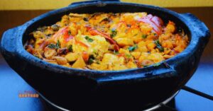 Moqueca de peixe servida em uma tradicional panela de barro, com peixe, camarão, temperos aromáticos e um caldo dourado, finalizada com ervas frescas.