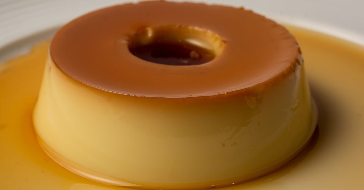 Pudim de leite condensado com calda caramelizada, textura lisa e brilhante, servido em um prato branco.