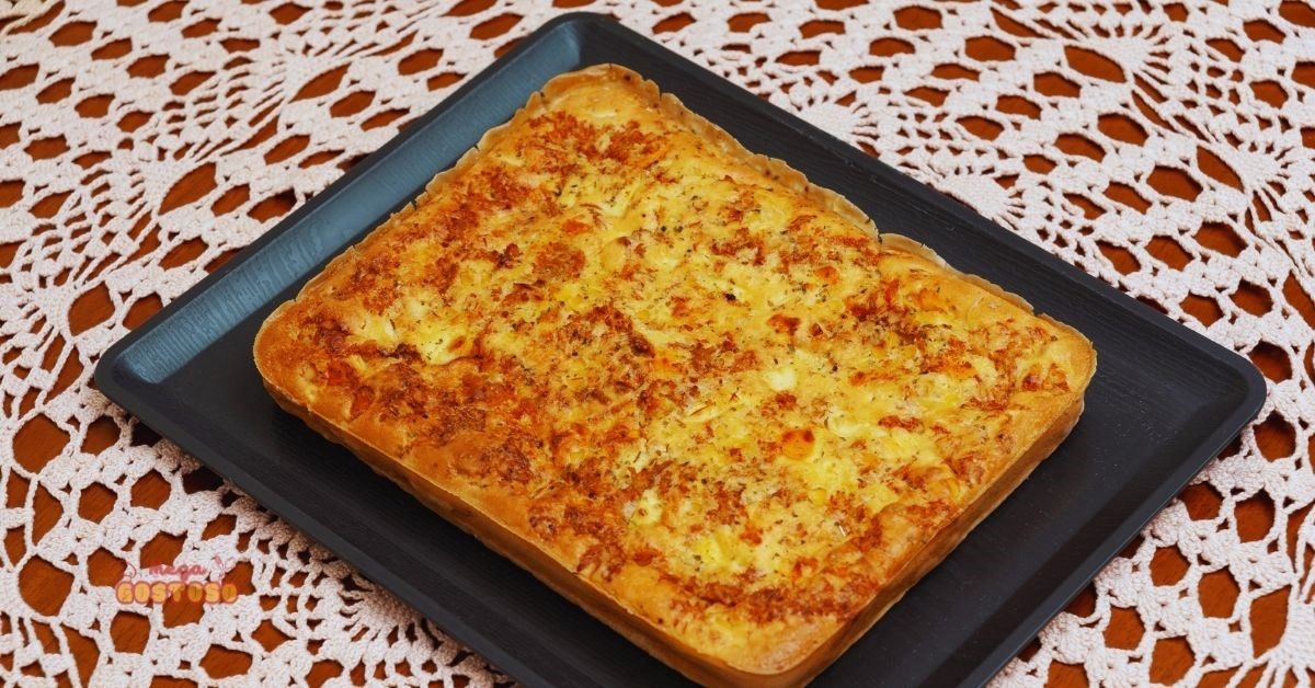 Torta salgada de liquidificador dourada e recheada, servida em uma assadeira, perfeita para um lanche prático e delicioso.