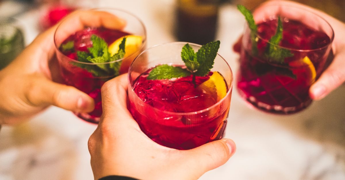 Copo de sangria de frutas vermelhas decorado com hortelã e fatias de laranja em uma mesa romântica