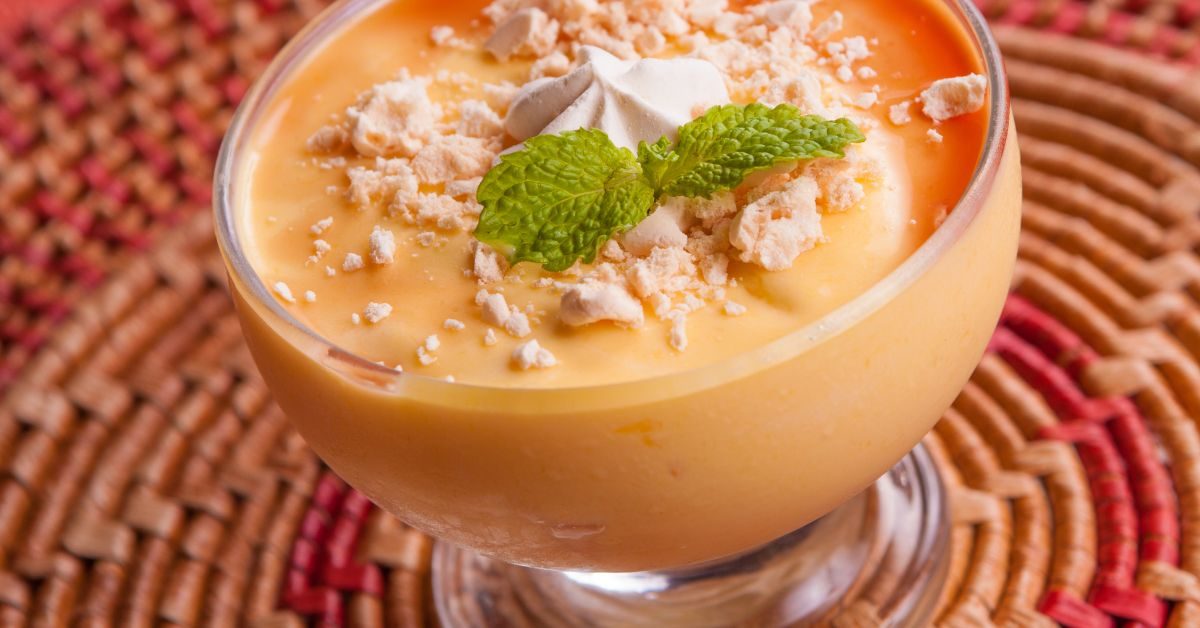 Creme de papaia cremoso, decorado com suspiros quebrados, uma folha de hortelã e calda doce.