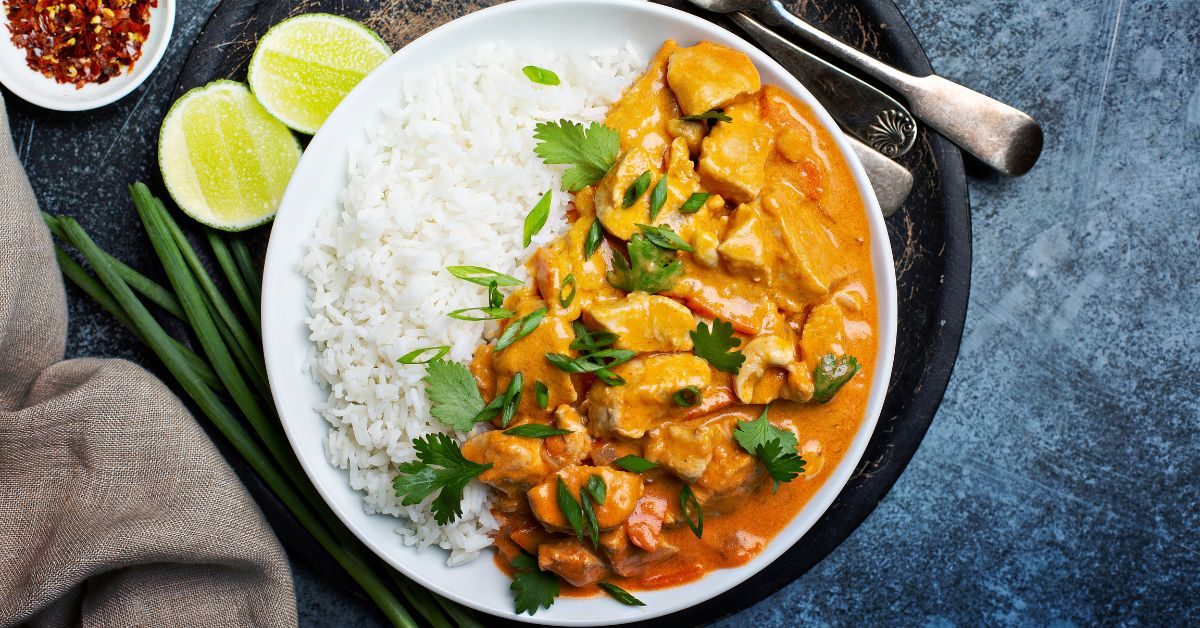Frango ao curry servido com arroz basmati e decorado com coentro fresco