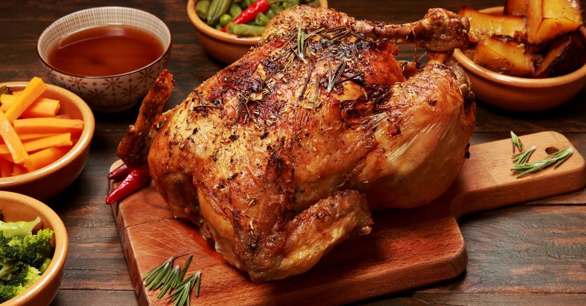 Frango assado dourado acompanhado de batatas e cenouras