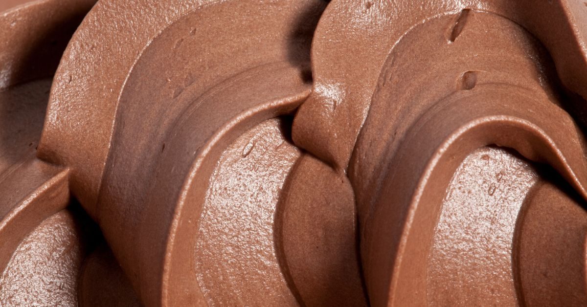 Mousse de chocolate com textura cremosa e aerada, destacando sua suavidade e brilho.