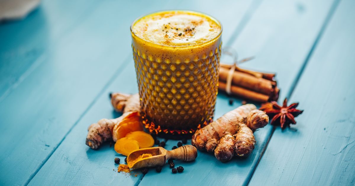 Xícara de golden milk com especiarias em uma mesa de madeira